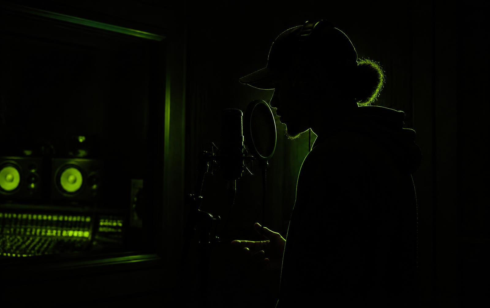 Independent artist recording vocals in a dark studio